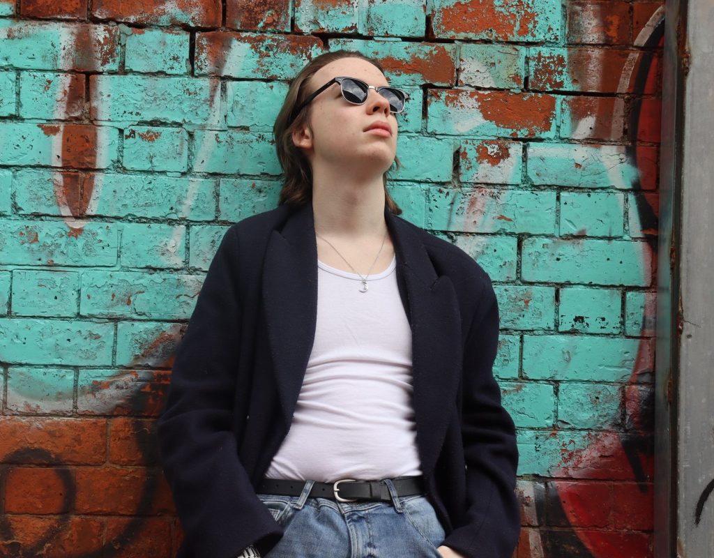 Joe posing in front of bright green graffiti.