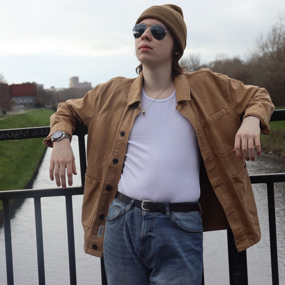 Joe leaning on a bridge's railings over a river.