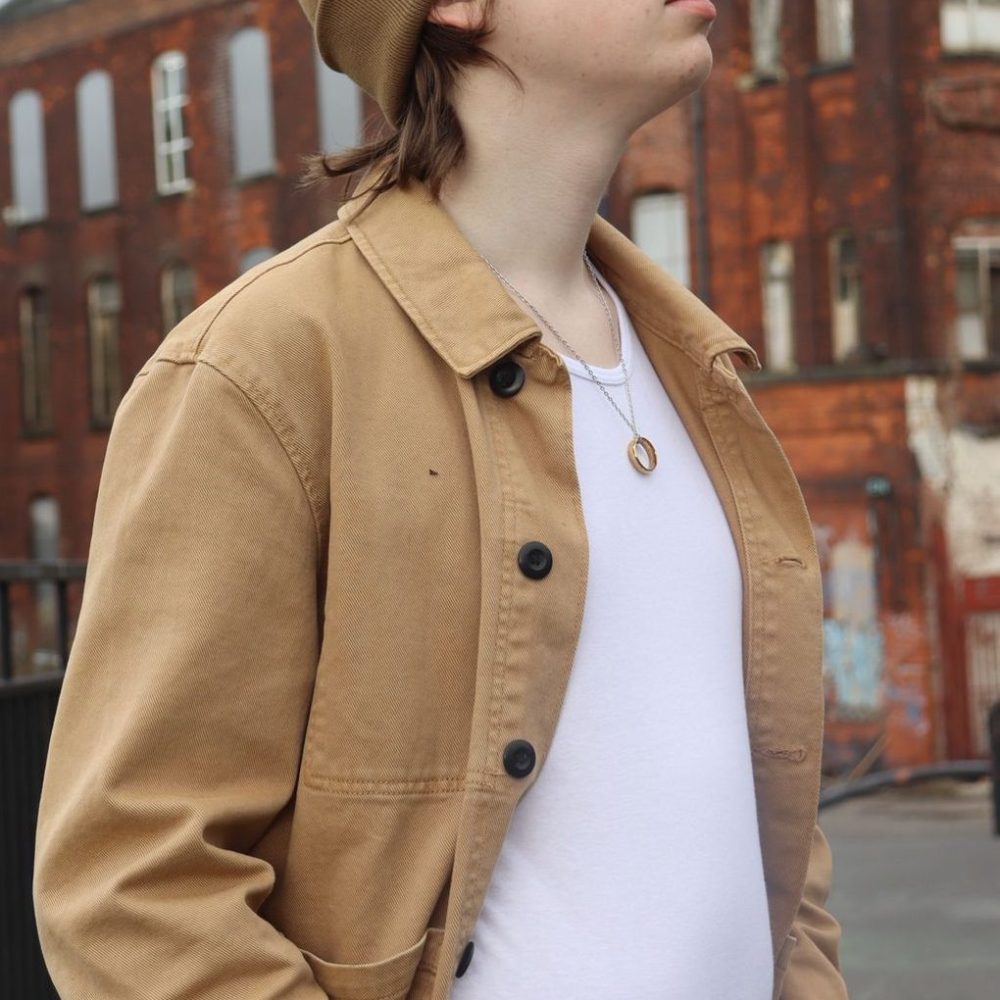 Joe looking to the right beside a brick building.