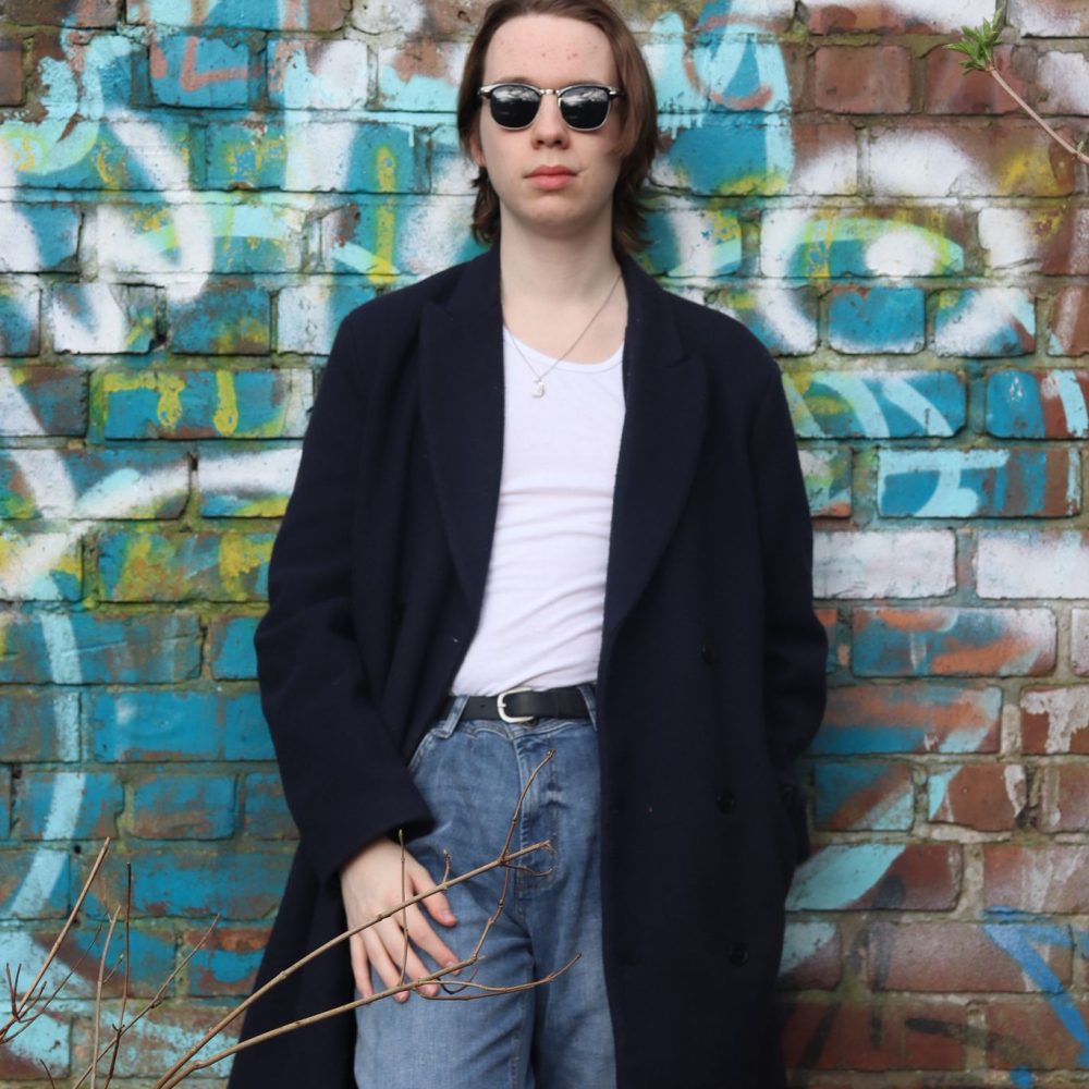 Joe leaning on a graffiti-covered wall.